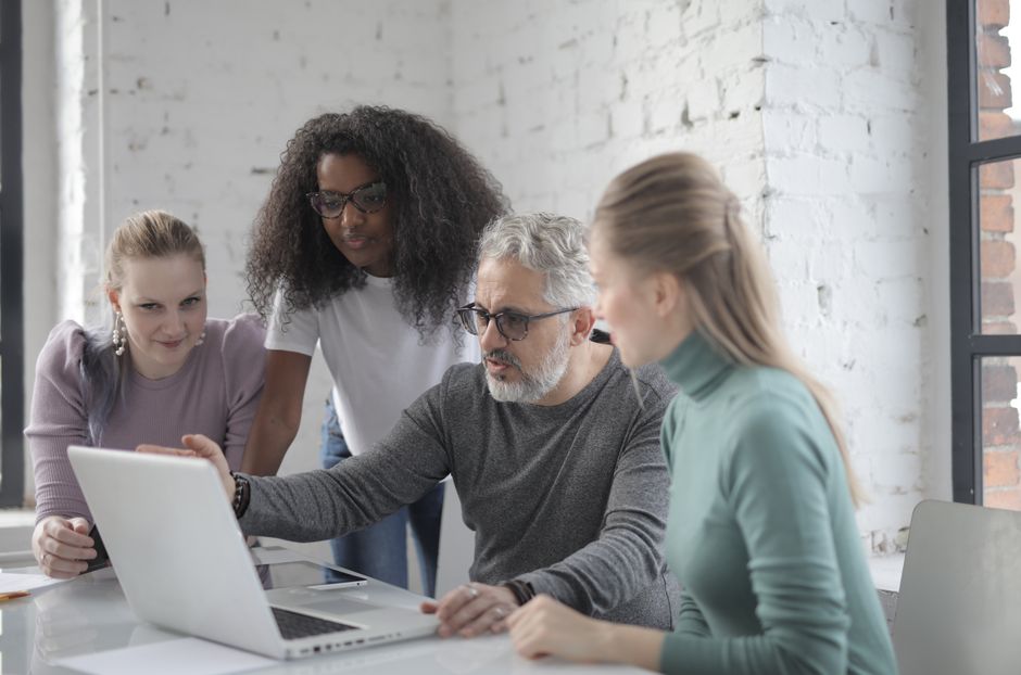 Diversidade nas Empresas — Focused bearded man sitting at table and working with laptop while discussing business project